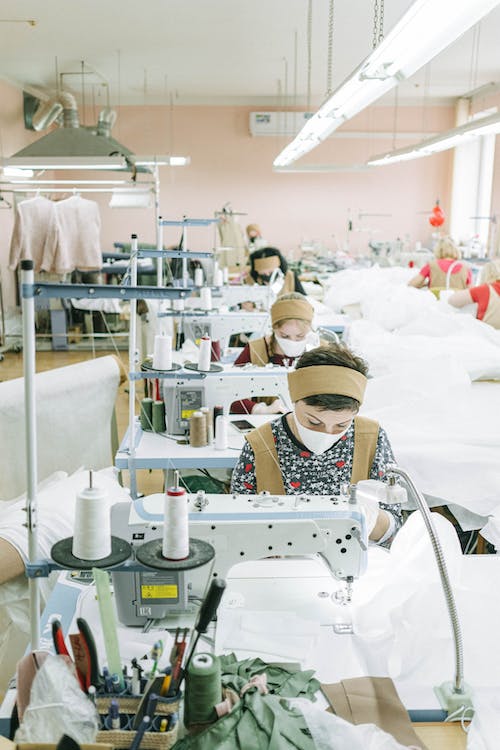 Fotografie Stock gratuită de femei care poartă măști de față care lucrează într-o fabrică de cusut